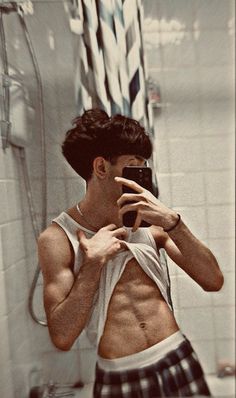 a shirtless man taking a selfie in front of a mirror with his cell phone