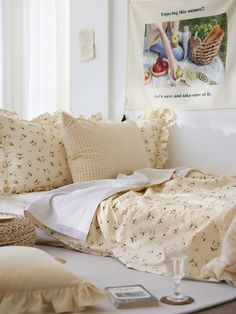 an unmade bed with pillows and blankets on top of it, next to a basket