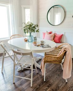 a white table and chairs in a room with wood flooring, round mirror on the wall