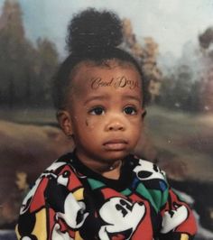 a young child with tattoos on her face and hair is sitting in front of a painting