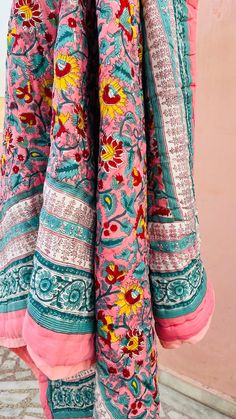 the back of a pink and blue dress with flowers on it, hanging from a hook