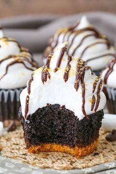 cupcakes with white frosting and chocolate drizzled on top are sitting on a plate