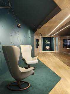 a chair and ottoman in an office with wood flooring, blue walls and green carpet