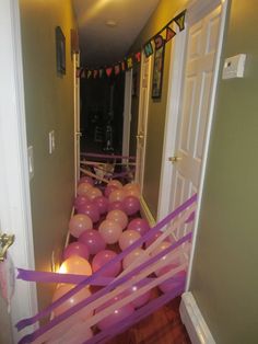 balloons and streamers are on the floor in front of an open door to a hallway