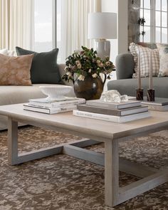 a living room filled with furniture and a coffee table in front of a couch covered in pillows