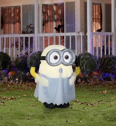 a large inflatable yellow and gray minion standing on top of a lush green field