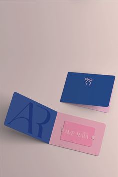 two blue and pink business cards sitting next to each other