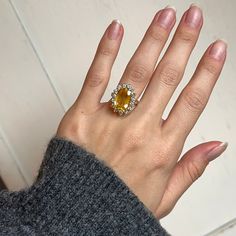 a woman's hand with a yellow diamond ring on top of her left hand