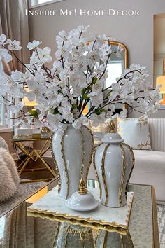 a vase with white flowers in it sitting on a table next to a mirror and couch