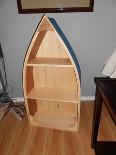 a wooden boat shaped bookcase sitting on top of a hard wood floor