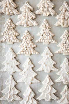 christmas cookies decorated with white icing and pine trees on a baking sheet, ready to be baked