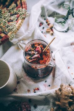 a jar filled with food sitting on top of a white cloth next to a cup