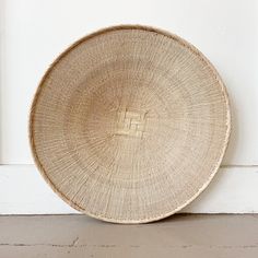 a woven plate sitting on top of a white wall