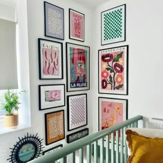 a baby's room with pictures on the wall and paintings on the wall above it