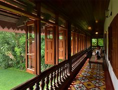 the balcony is lined with wooden doors and decorative tile flooring, along with green grass