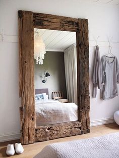 a mirror sitting on top of a wooden floor next to a bed