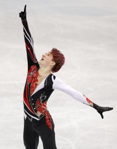 a female figure skating on the ice with her arms in the air and one hand up