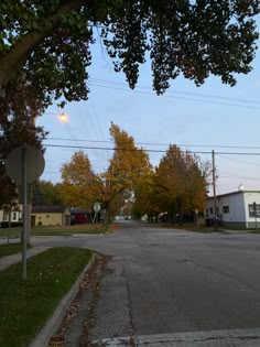 an empty street with no cars on it and houses in the background at dusk or dawn