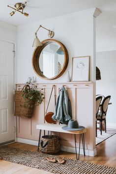 a room with a bench, mirror and coat rack