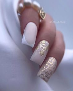 a woman's hand with white and gold manies on her nails, which are decorated