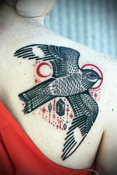 the back of a woman's shoulder with a bird tattoo on her upper arm