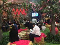 people are sitting on hay bales in the middle of a room filled with plants and flowers