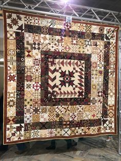 a large quilt hanging on the side of a wall in a room with metal poles