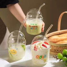 three glasses filled with drinks sitting on top of a table next to grapes and bread