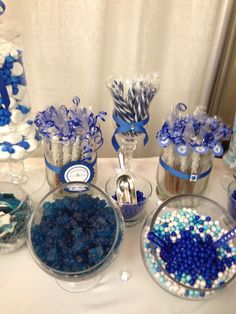 blue and white candies in glass bowls on a table with other candy items around them