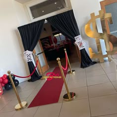 a red carpeted entrance way with gold barriers and black drapes on the door