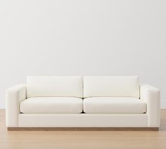 a white couch sitting on top of a hard wood floor next to a white wall