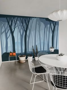 a white table and chairs sitting in front of a wall with trees painted on it