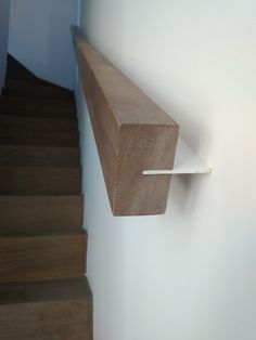 a wooden shelf mounted on the side of a wall next to a stair case in a house