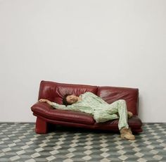 a person laying on a red couch in a room with black and white checkered flooring