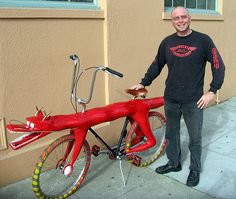 a man standing next to a red bike