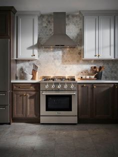 a stove top oven sitting inside of a kitchen next to wooden cabinets and counter tops