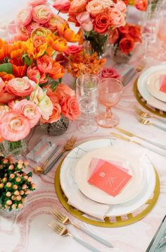 the table is set with pink and orange flowers