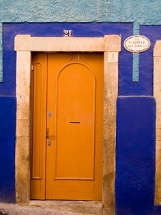 an orange door in front of a blue wall