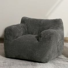 a grey chair sitting on top of a carpeted floor next to a white wall