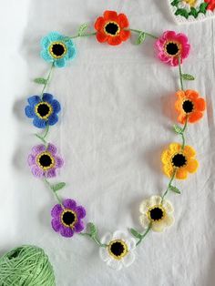 crocheted flowers are arranged in a circle on a white tablecloth next to a ball of yarn