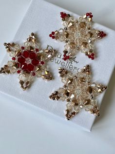 two snowflakes are sitting on top of a white napkin with red and gold beads