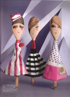 three wooden dolls are standing in front of a purple wall and one is wearing a black and white striped dress