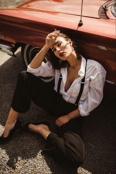 a woman sitting on the ground next to a car