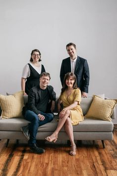 three people sitting on a couch posing for the camera