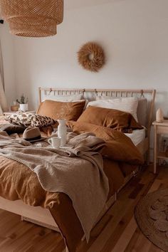 a bed with brown sheets and pillows in a bedroom next to a table, rugs and window