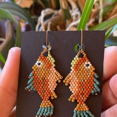 a pair of earrings made out of seed beads with fish design on the front and back