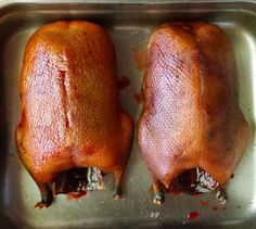 two raw chickens sit in a metal pan