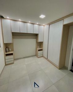 an empty room with white walls and beige cupboards on either side of the closet