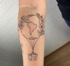 a person with a tattoo on their arm holding a gift box in the shape of a balloon