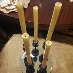 three candles sitting on top of a glass plate in front of a table with a brown cloth